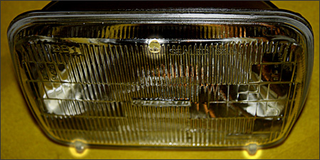What is the primary reason there are three bumps (also known as pads or nibs) on the lens of a sealed beam headlight?